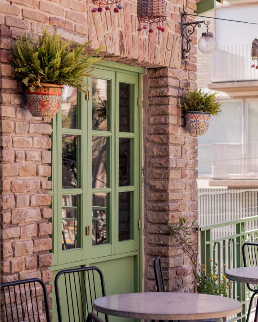 Fachada de La Mulita con su puerta verde y mesas en la vereda